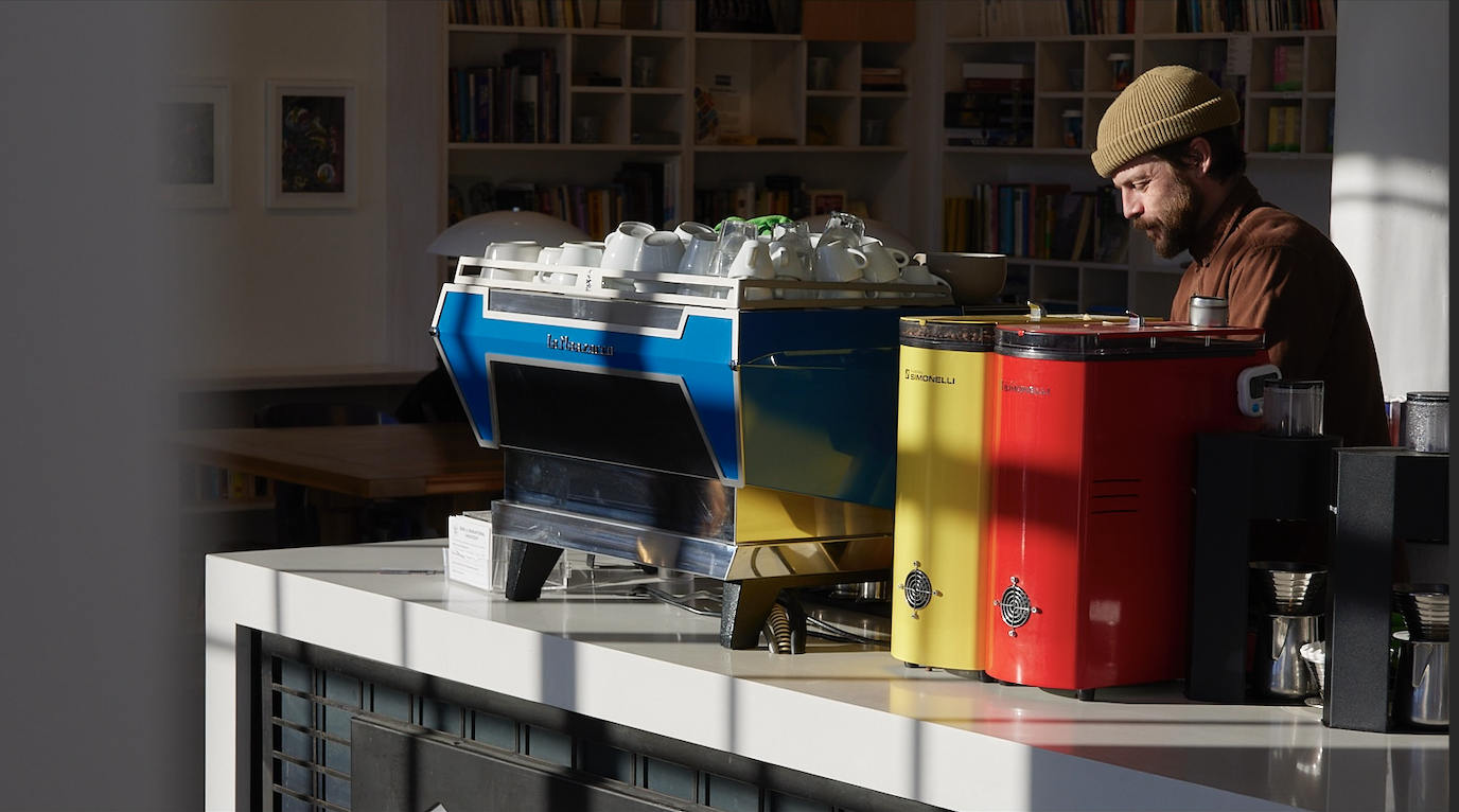 a blue espresos machine next to a yellow grinder and a red grinder at blueprint coffee in st. louis